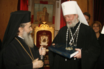 Ο Μακαριώτατος προσφέρει στη συνοδεία σταυρούς εκ μαργαριταρορρίζης.